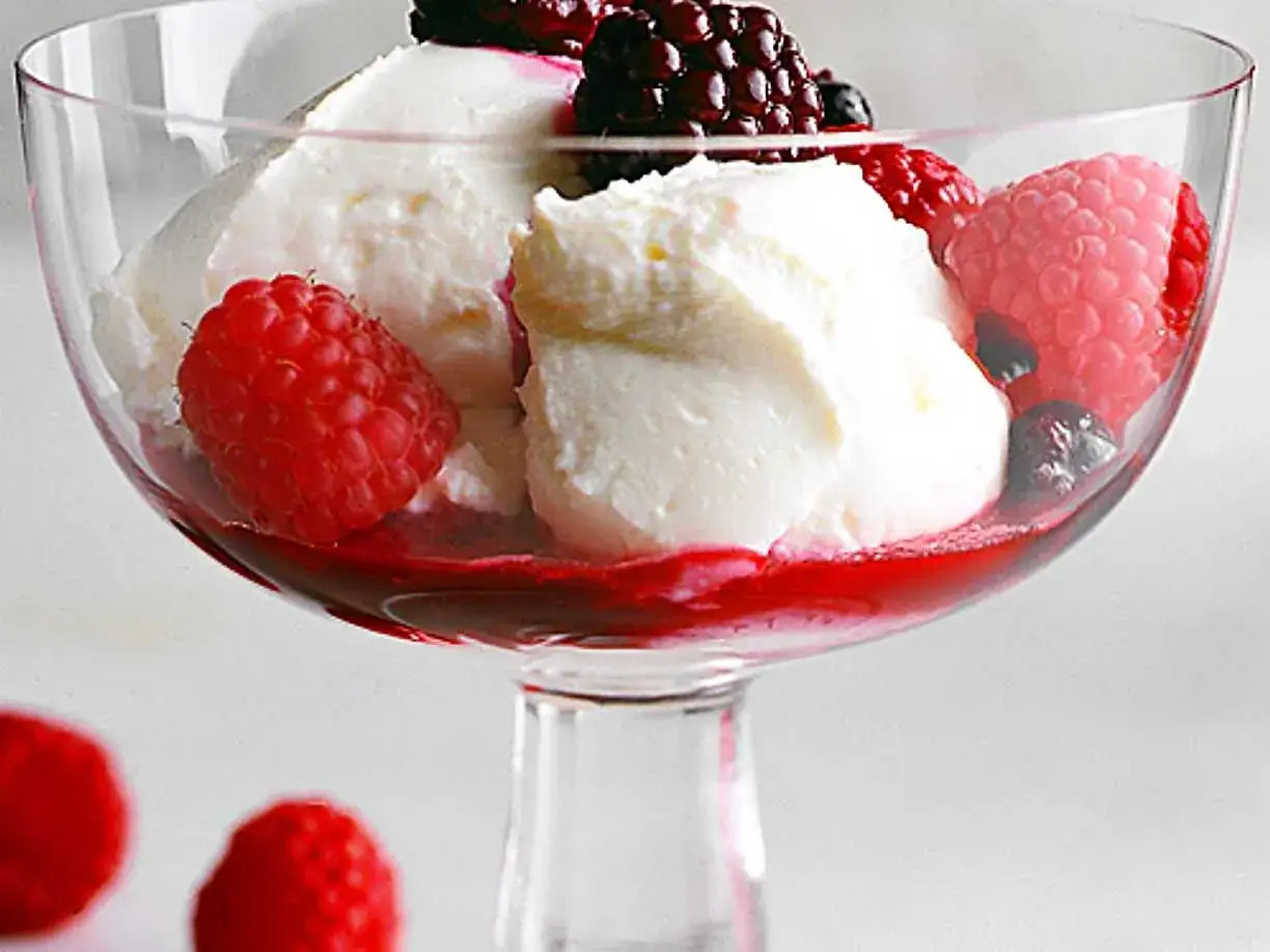 Ljuvlig hemmagjord glass med färska hallon och björnbär i ett elegant glas. En perfekt sommardessert!