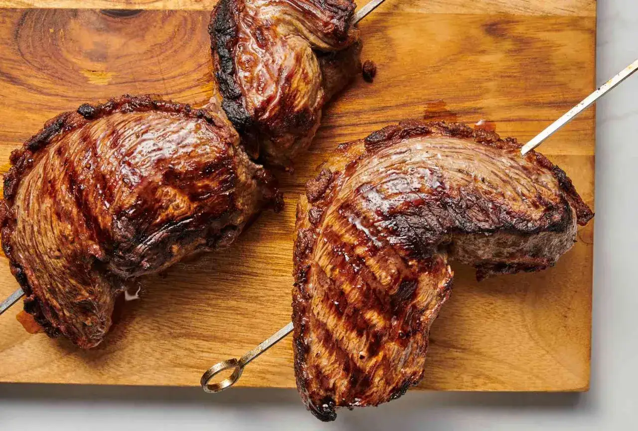 Perfekt grillad picanha på ett skärbräde. Köttet har en fin yta med grillränder och saftig insida.