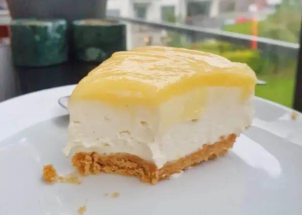 En krämig bit citron cheesecake med krispig botten, redo att avnjutas.
