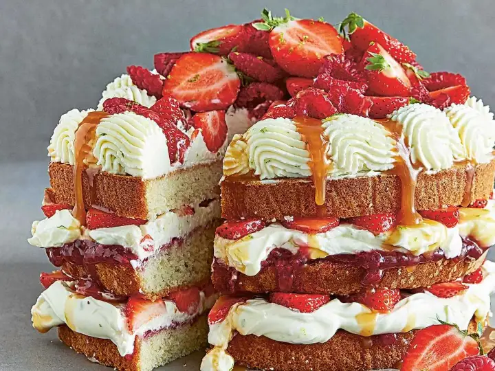 En generös tårta med lager av sockerkaka, vispgrädde, färska jordgubbar och en härlig jordgubbsmousse tårtfyllning, toppad med mer grädde och karamellsås.